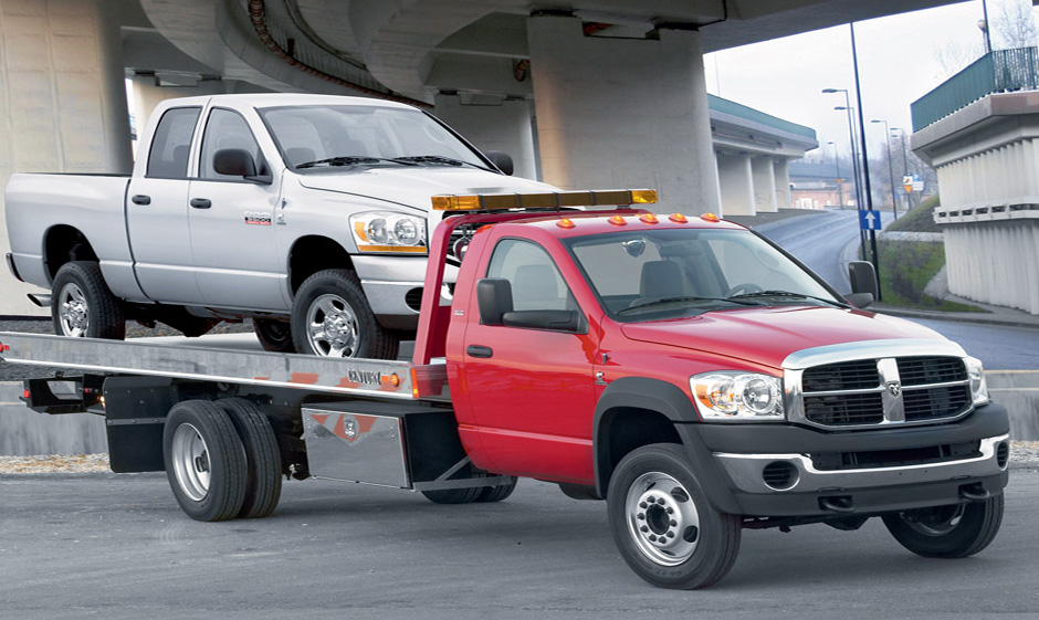 Photo of Red Dodge Ram flatbed towing truck with Pickup Truck in it.